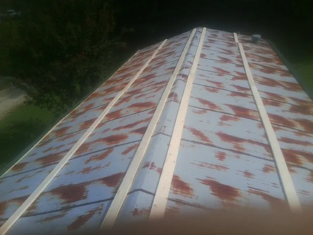 Rusted metal roof panels with new wood purlins before replacement — Storm Damage Roof Repair in Strasburg by Roofing Brothers
