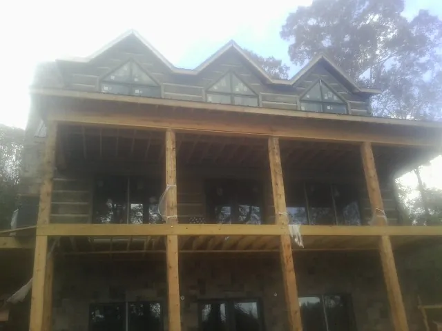 Dormers and porch framing on a large log home under construction — Roof Coating work by our crew in Strasburg